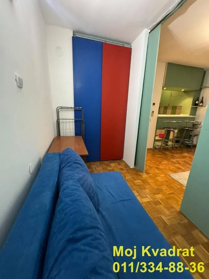 Dnevna soba sa plavom garniturom i pogledom na kuhinju.