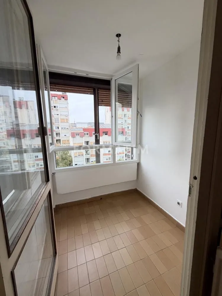 Zastakljena terasa sa keramičkim pločicama i pogledom na grad.