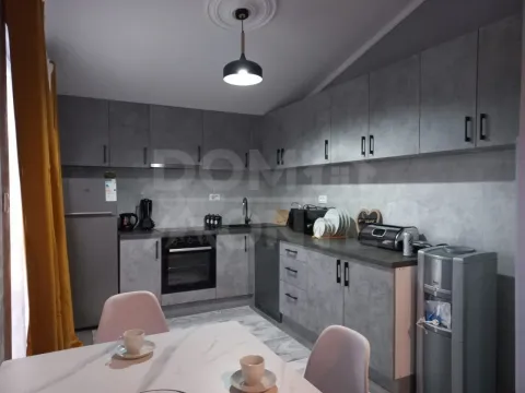 Modern kitchen with grey cabinets and a dining table in the foreground. - image 3
