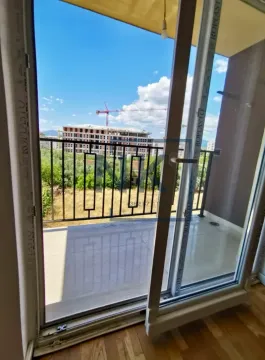 View through the balcony door to the terrace and surrounding buildings under construction. - image 8