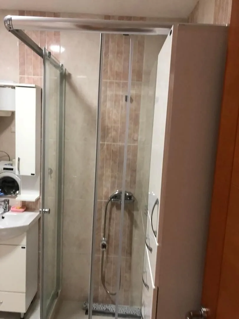 Small bathroom with a shower cabin, washbasin, and white cabinetry.