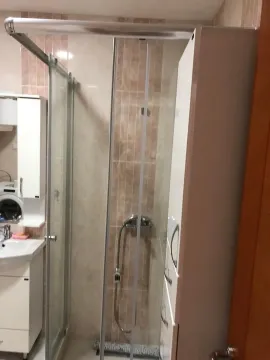 Small bathroom with a shower cabin, washbasin, and white cabinetry. - image 13