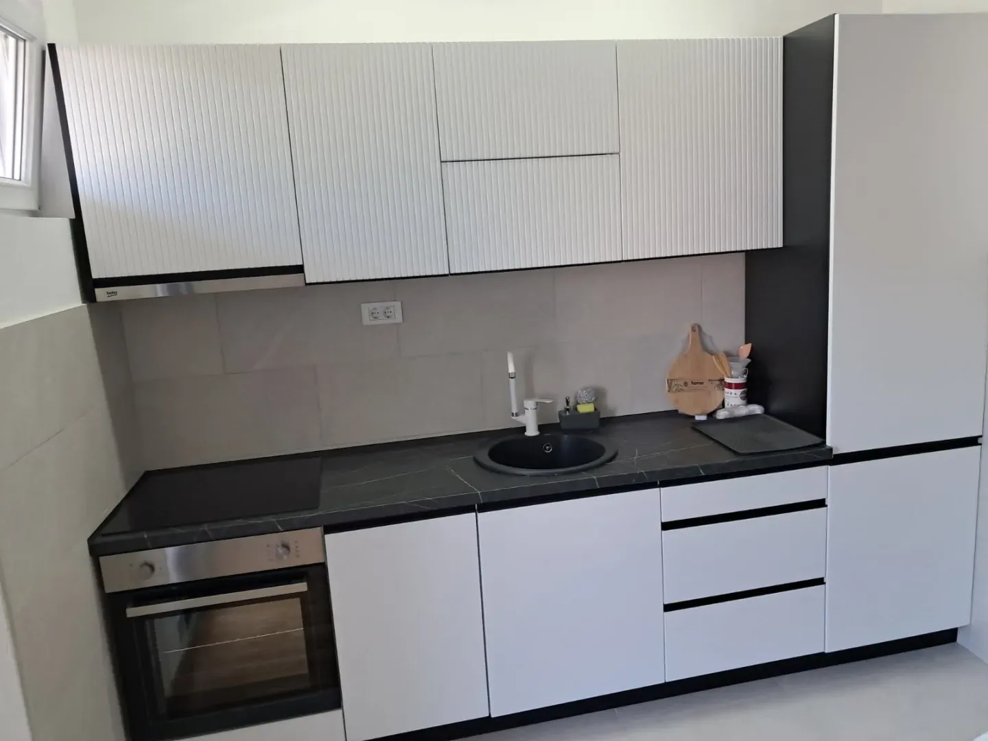 Modern kitchen with white cabinetry and a dark countertop.