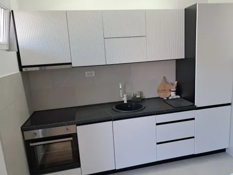 Modern kitchen with white cabinetry and a dark countertop. - image 8