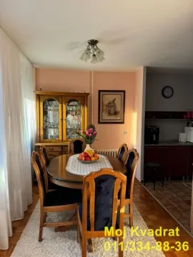 Trpezarija sa drvenim stolom, stolicama i vitrinom u dnevnom boravku. - image 4