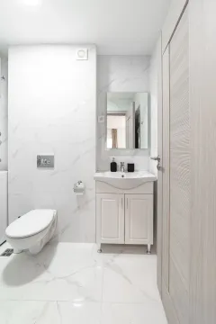 Moderne opremljeno kupatilo sa bijelim mermernim pločicama i umivaonikom sa ormarićem. - image 12