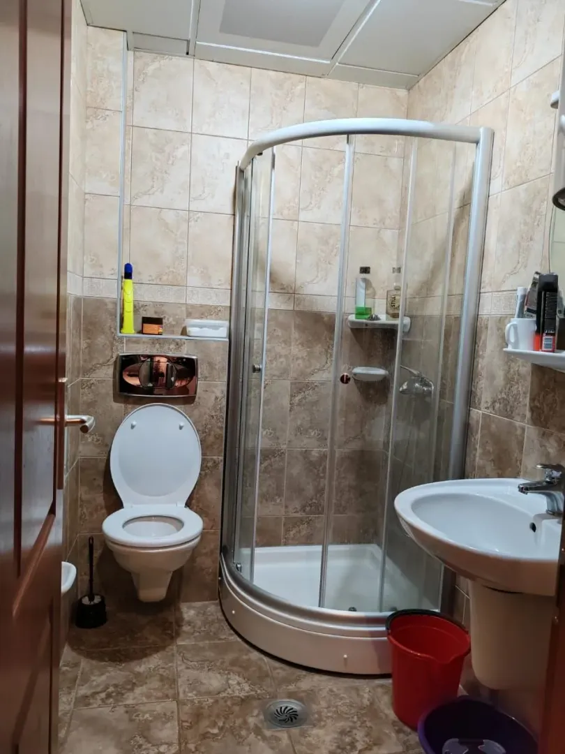 Smaller bathroom with a shower cabin, sink, and toilet, tiled with ceramic tiles.