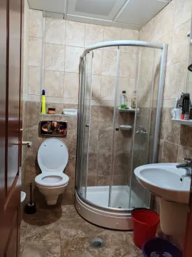 Smaller bathroom with a shower cabin, sink, and toilet, tiled with ceramic tiles. - image 13