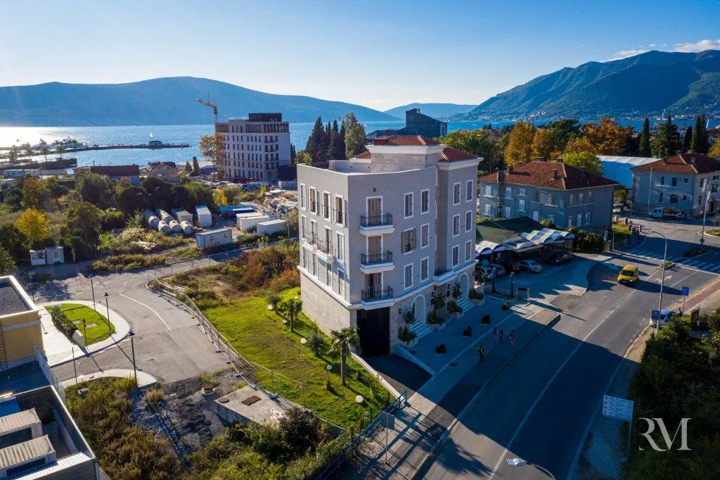 Aerial view of a multi-story building near the coast and road.