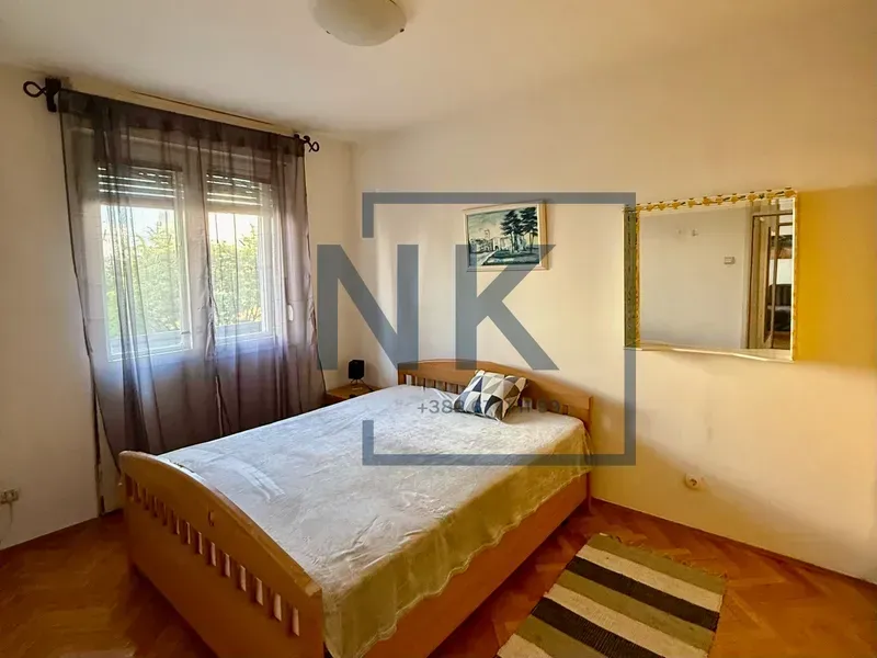 A bedroom with a double bed, a window, and a wall mirror.