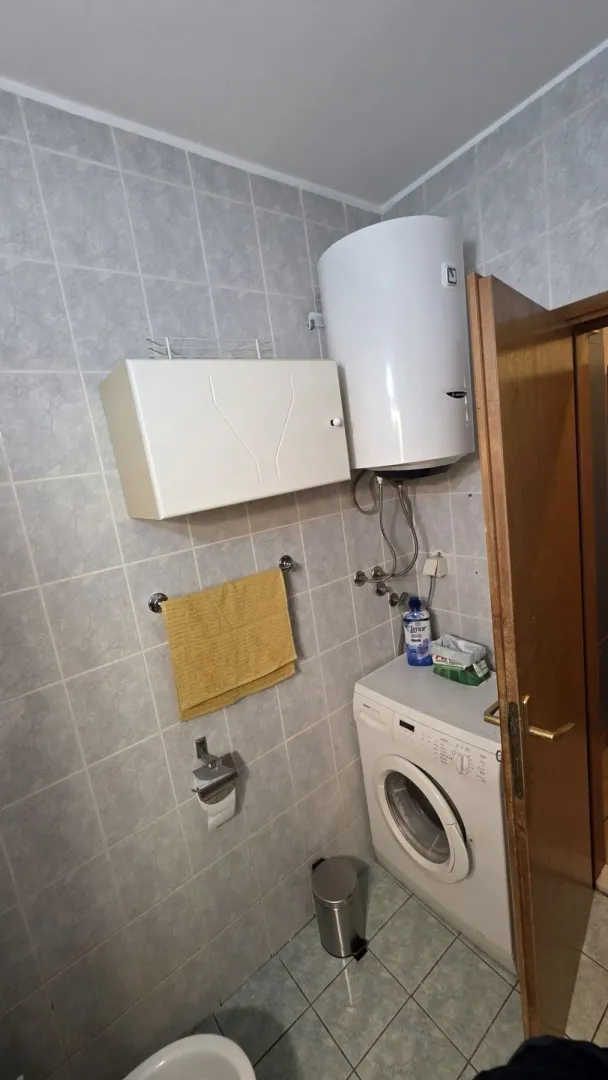 Part of a bathroom featuring a washing machine, water heater, and a wall cabinet.