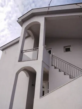 Exterior view of a two-story house featuring arched architectural details and outdoor stairs. - image 9