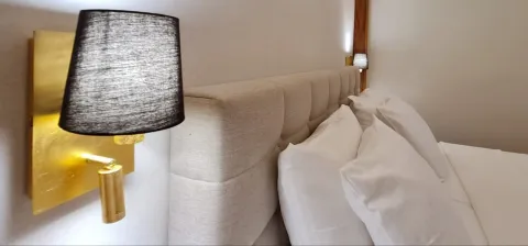 Krupni kadar uzglavlja kreveta sa zidnom lampom u spavaćoj sobi. - image 12