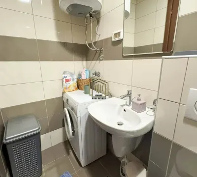 Manje kupatilo sa umivaonikom, veš mašinom i bojlerom na zidu. - image 4