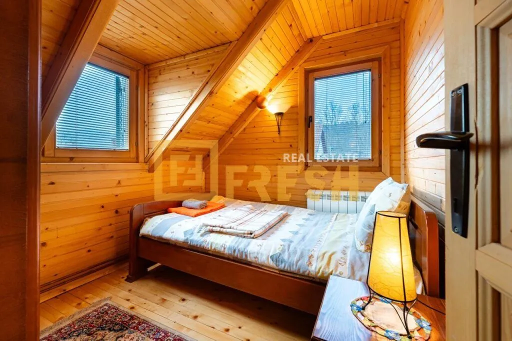 Drvenom obložen potkrovni apartman sa krevetom i prozorima.