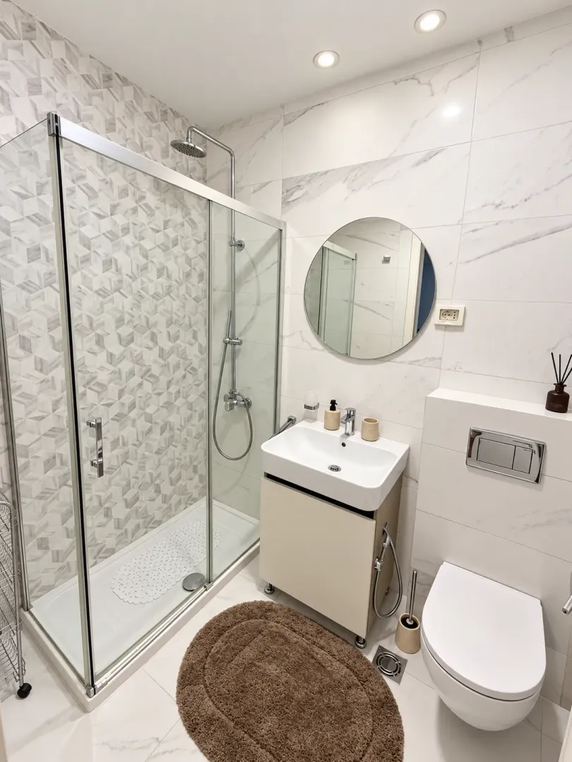 Modern bathroom with a shower cabin, washbasin, and toilet.