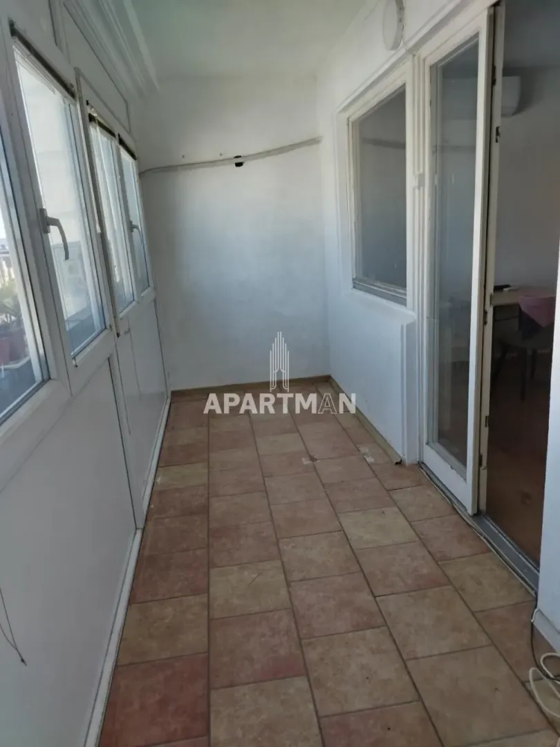 Zastakljeni balkon sa keramičkim pločicama na podu.