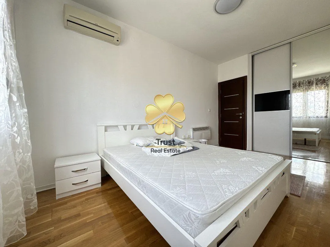 Bright bedroom with a white bed, nightstand, and wardrobe.