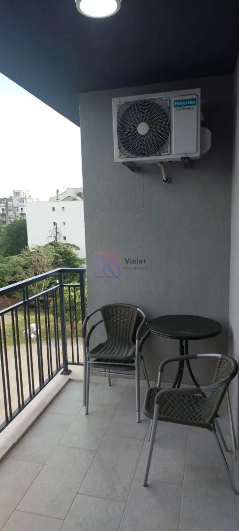 Manji namješten balkon sa stolom i stolicama.