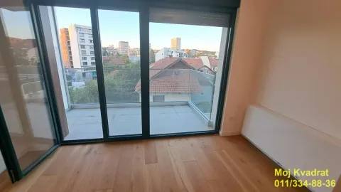 Pogled iz sobe na terasu i okolne zgrade kroz velika staklena vrata. - image 2