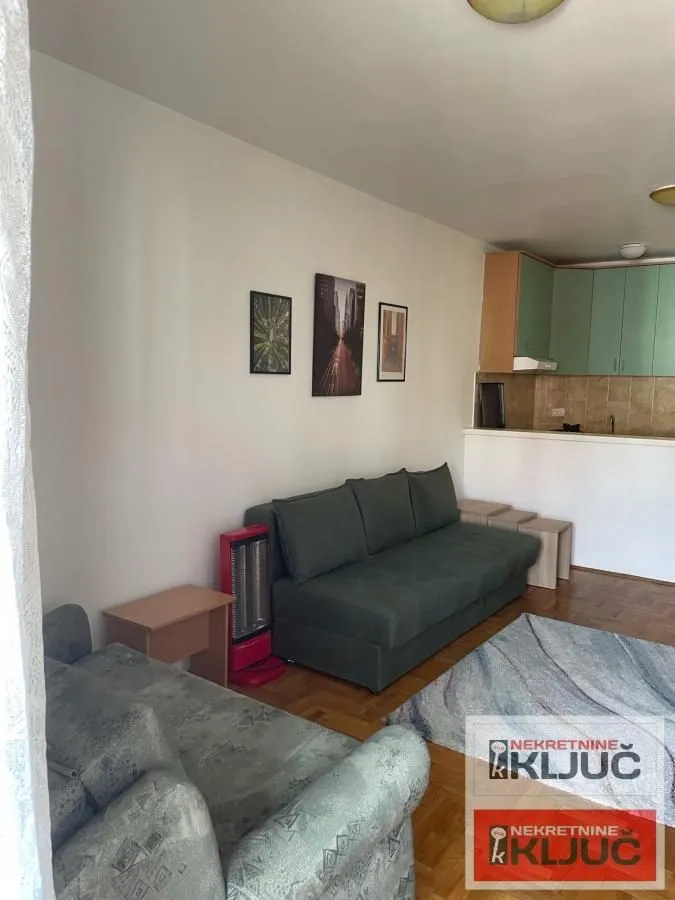 Living room with a sofa set and a view of the kitchen in the background.