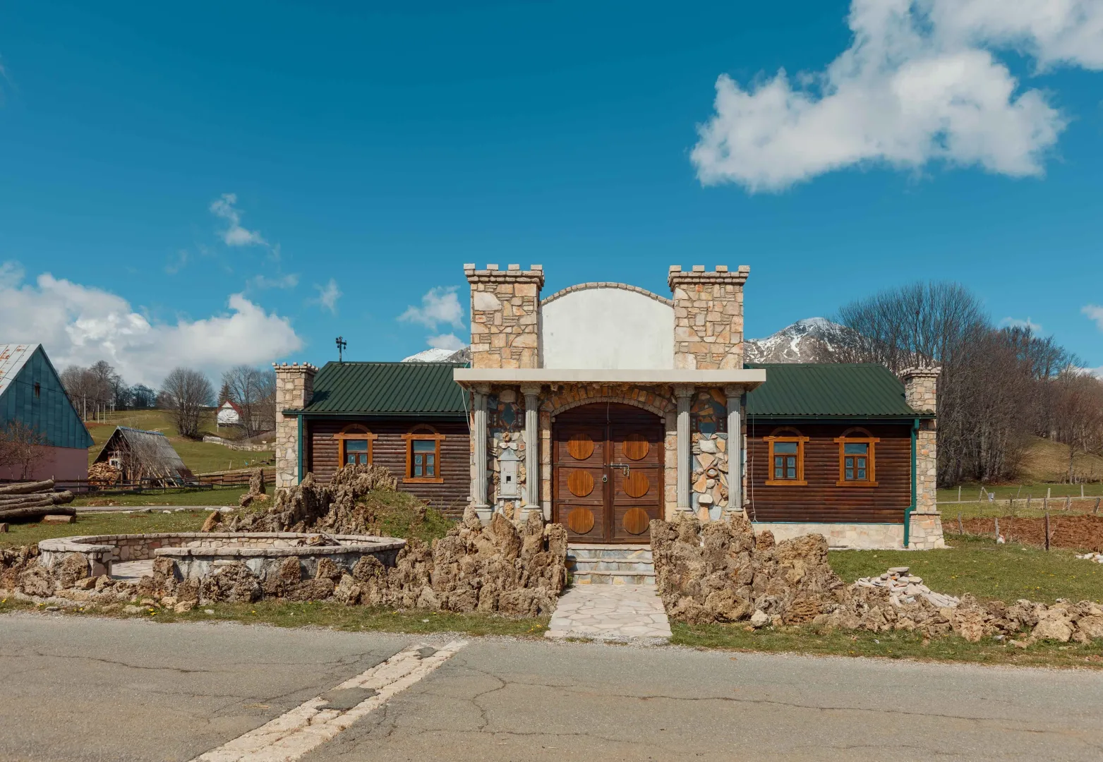 Exterior of an unusual house with stone and wooden details and a yard.