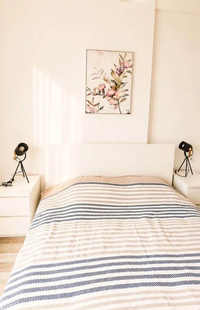 Bright bedroom with a double bed, white nightstands, and wall art.