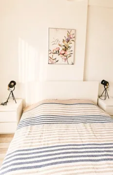 Bright bedroom with a double bed, white nightstands, and wall art. - image 7