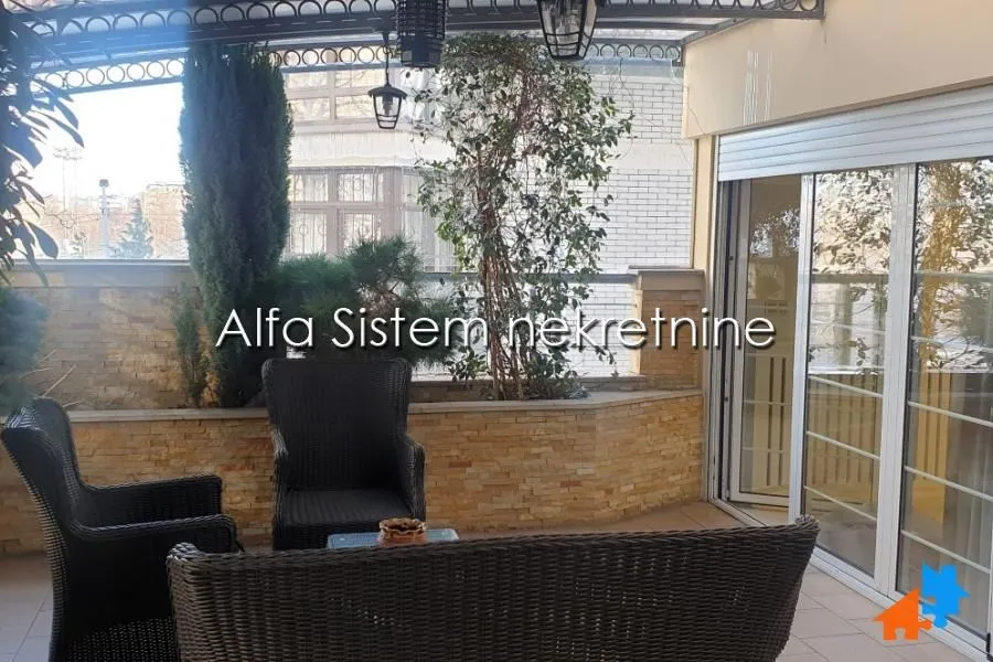 Furnished covered terrace with seating set and greenery.