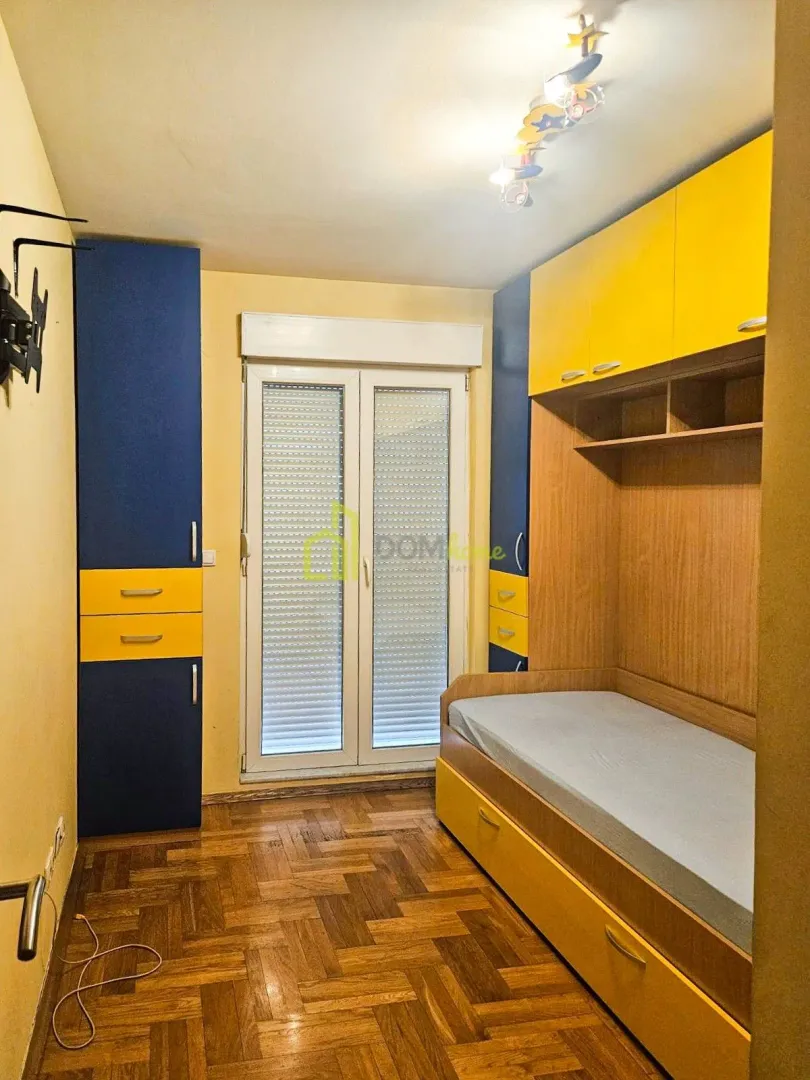 Children's bedroom with a bed, built-in wardrobes, and parquet flooring.