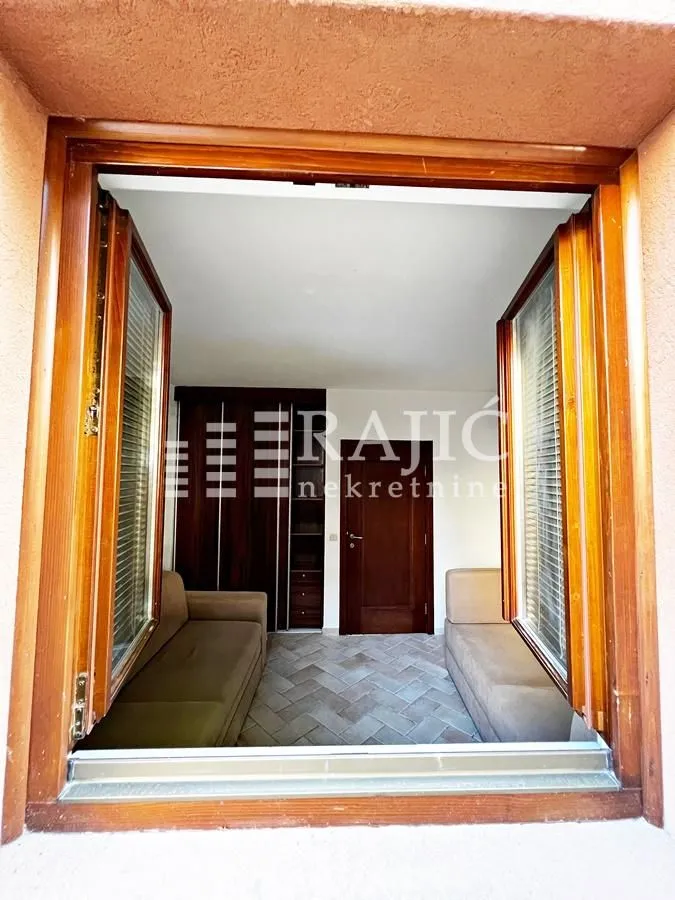 View through a wooden window into a furnished room with sofas and a wardrobe.