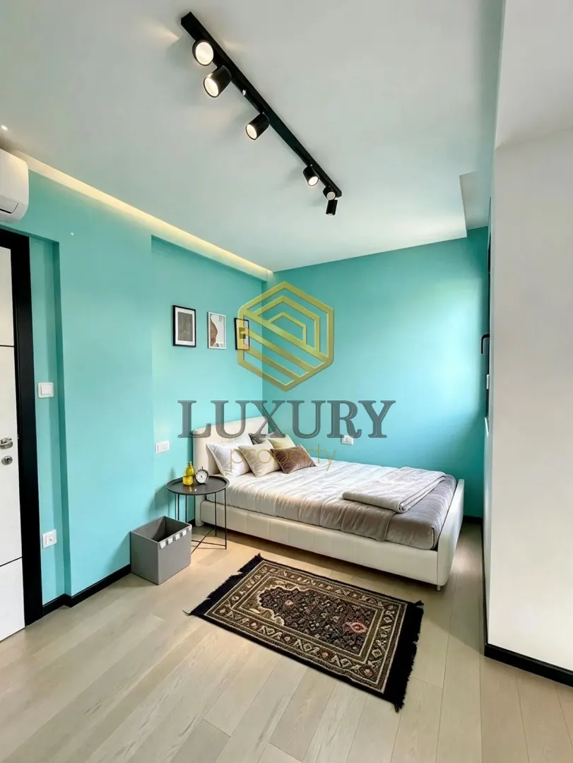 Modern bedroom with a bed and a turquoise wall.