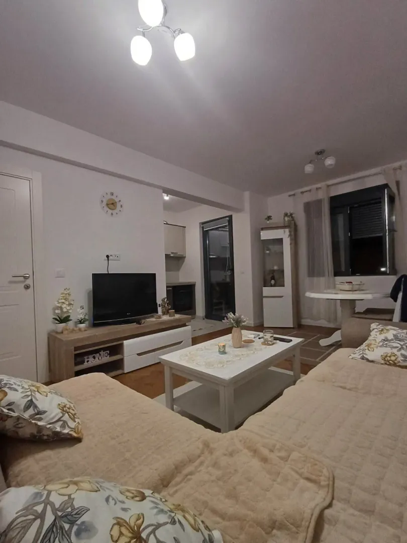 Namještena dnevna soba sa garniturom, stočićem i televizorom.