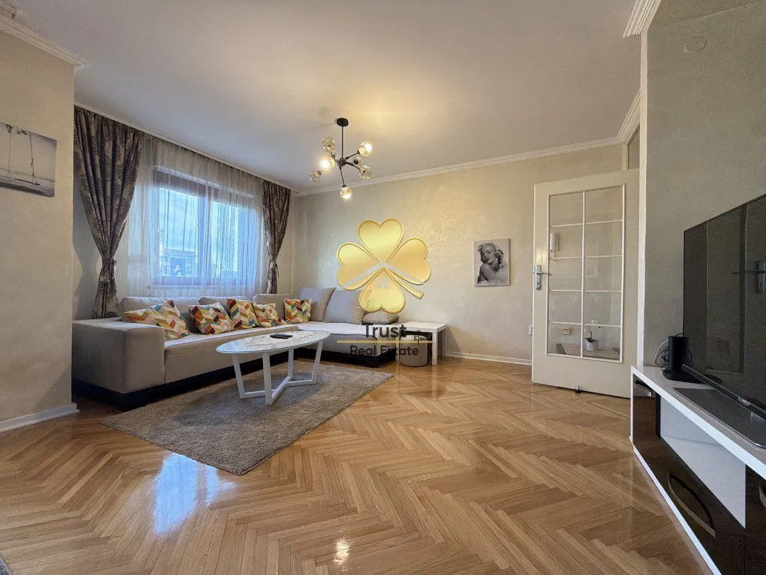 Spacious living room with sofa set and parquet flooring.