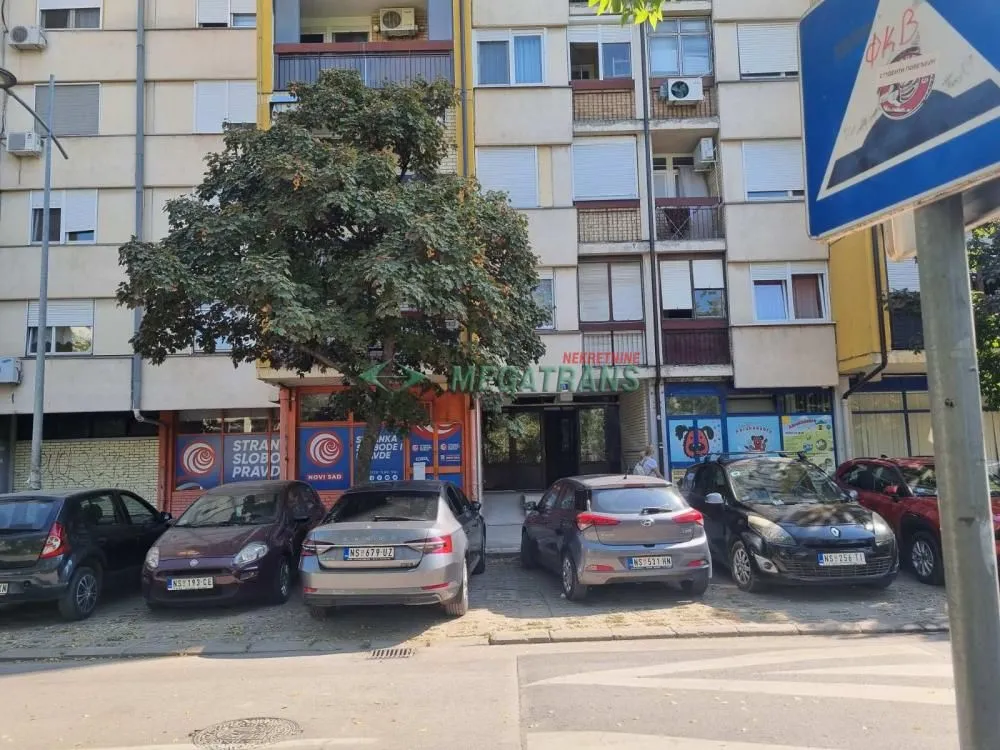 Pogled na spoljašnjost zgrade sa parkingom ispred ulaza.