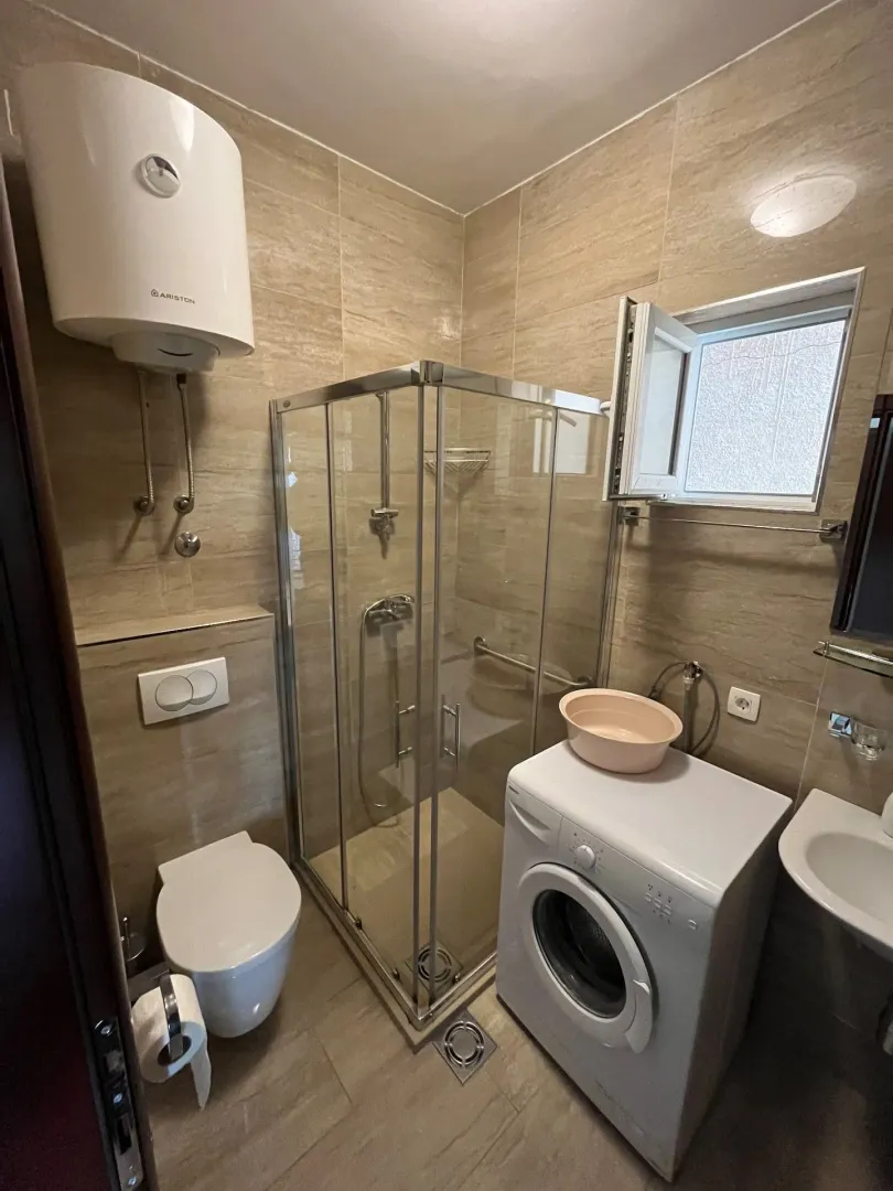 Small bathroom equipped with a shower cabin, sanitary fixtures, and a washing machine.
