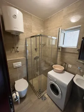 Small bathroom equipped with a shower cabin, sanitary fixtures, and a washing machine. - image 5