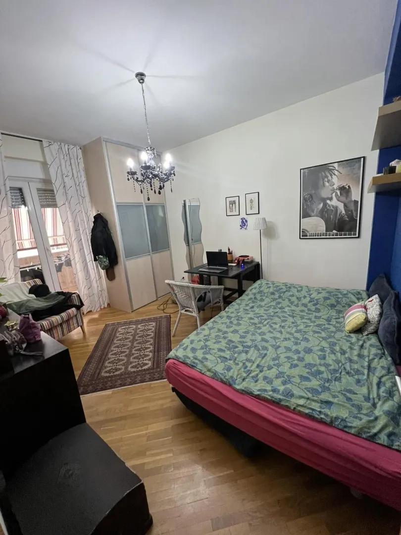 Svijetla spavaća soba sa velikim krevetom, radnim stolom i ugradnim garderoberom.