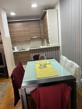 Trpezarijski sto sa stolicama i kuhinja u pozadini. - image 11