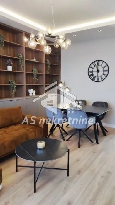 Living room with sofa, dining area, and large wall shelving unit.