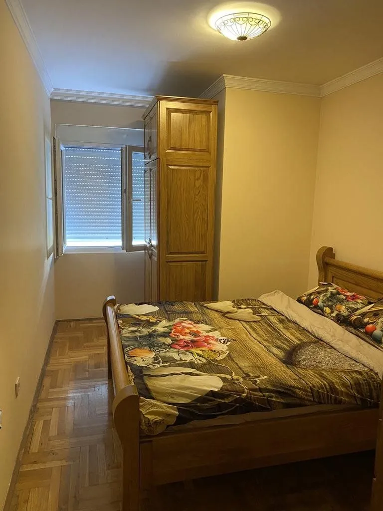 Furnished bedroom with a double bed, wooden wardrobe, and a window.