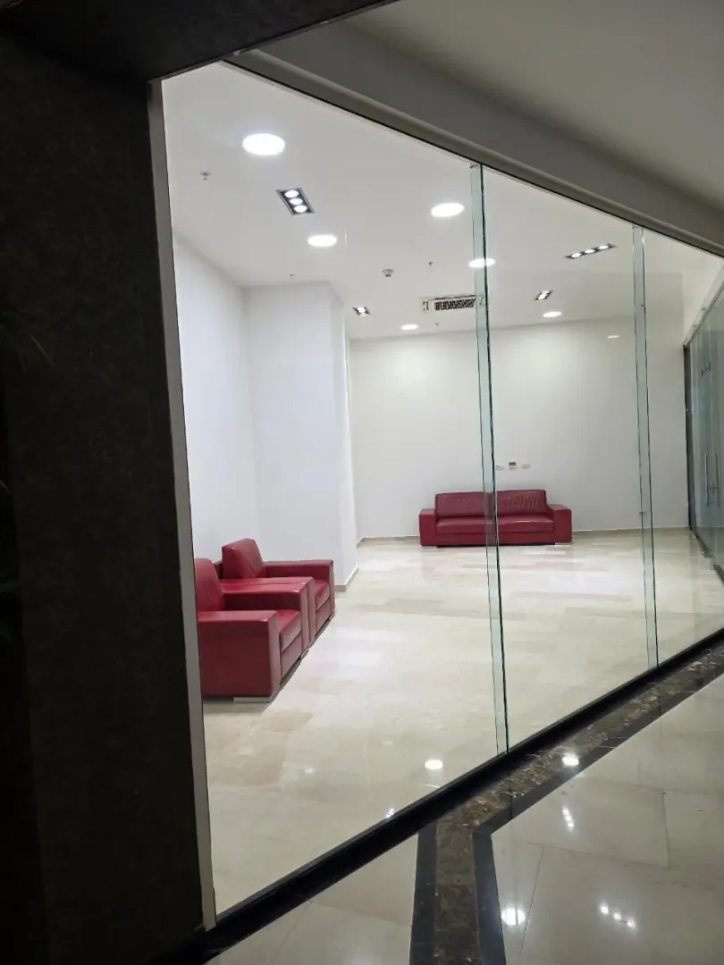 Empty office space or lounge area with red leather furniture behind a glass partition wall.