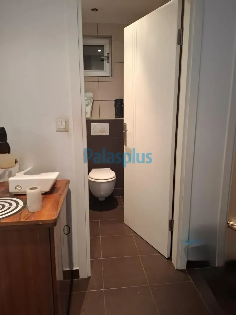View from the hallway into the bathroom with sanitary fixtures and an open door.