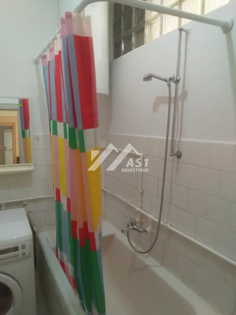 Bathroom with a bathtub, shower set, and a colorful curtain.