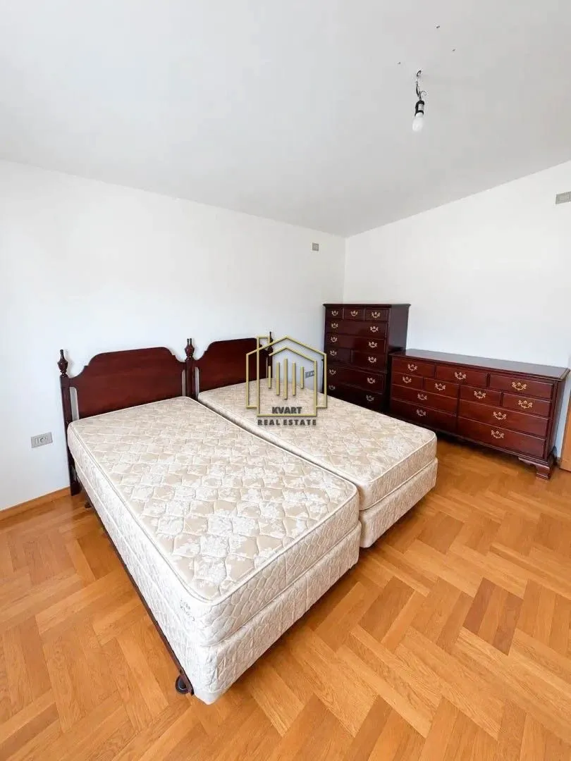 Bedroom with two beds and wooden dressers.