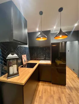 Moderna kuhinja sa tamnim elementima i drvenom radnom površinom. - image 6
