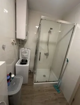 Smaller bathroom with a shower cabin, water heater, and washing machine. - image 9