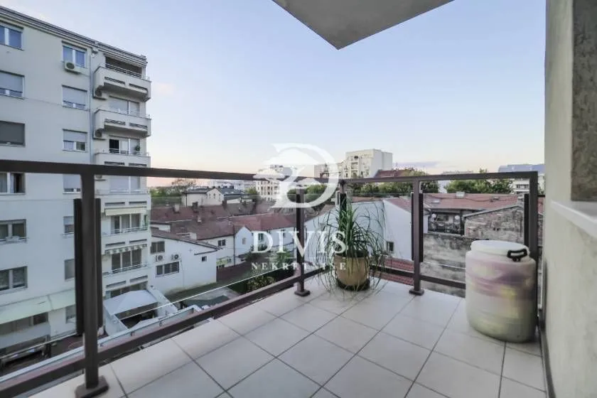 Natkriveni balkon sa pločicama i pogledom na gradsko naselje.