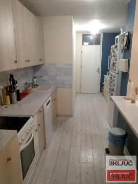 Dugačka kuhinja sa drvenim elementima, sudoperom i ugradnim aparatima. - image 3