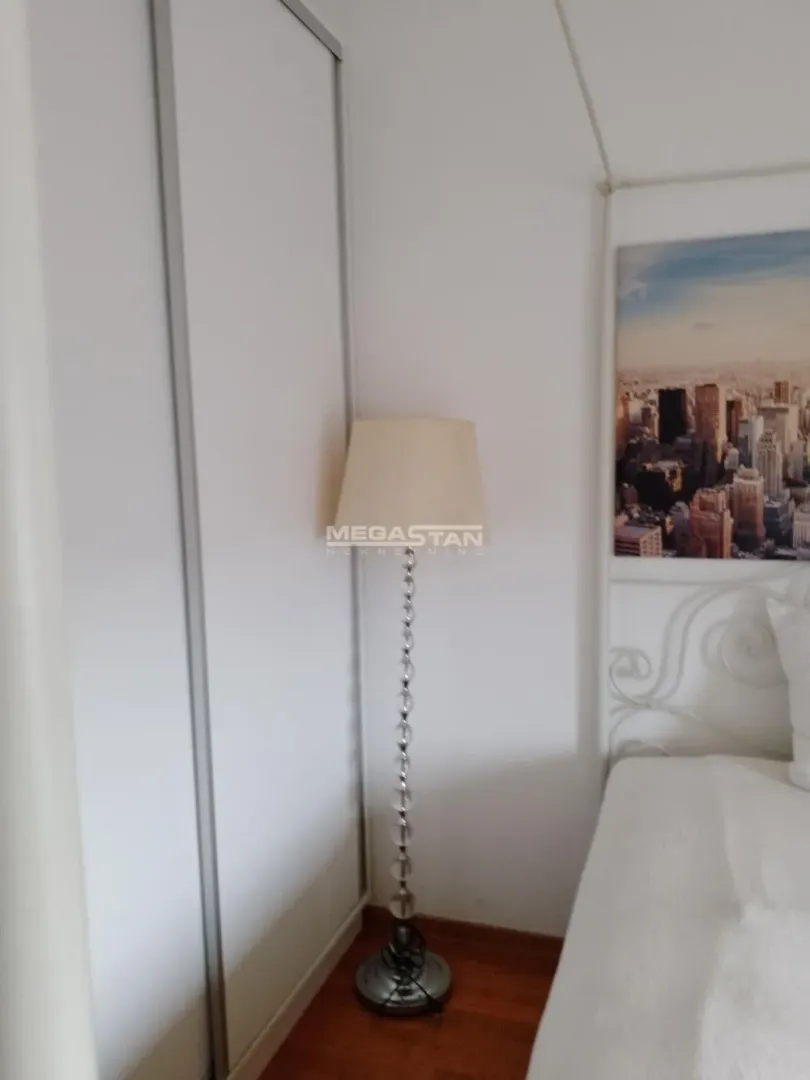 Pogled na spavaću sobu sa krevetom, garderoberom i ukrasnom lampom.